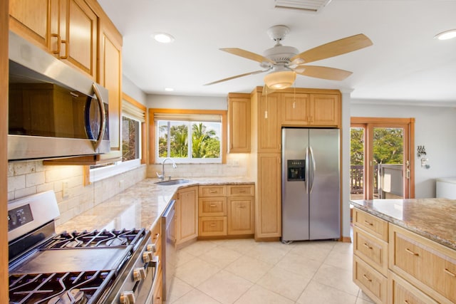 kitchen featuring appliances with stainless steel finishes, light brown cabinets, a sink, and light stone countertops