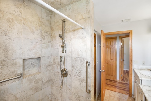 bathroom featuring visible vents, vanity, and tiled shower