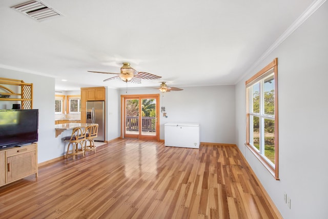 unfurnished living room featuring light wood-type flooring, baseboards, visible vents, and crown molding