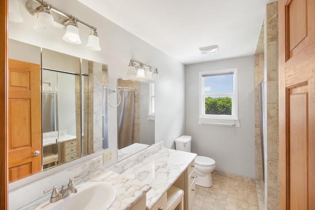 bathroom with baseboards, a tile shower, vanity, and toilet