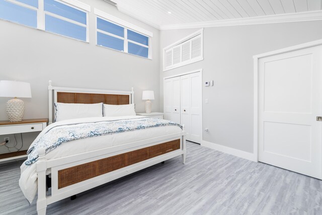 bedroom featuring crown molding, a closet, wood finished floors, baseboards, and a high ceiling