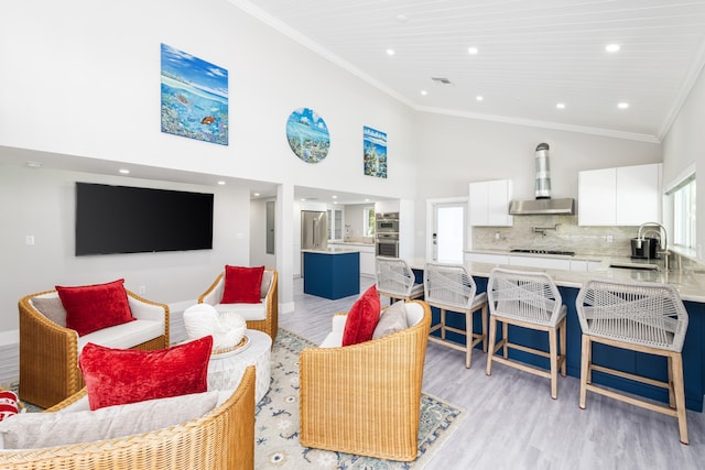 living area featuring a healthy amount of sunlight, high vaulted ceiling, crown molding, and light wood finished floors