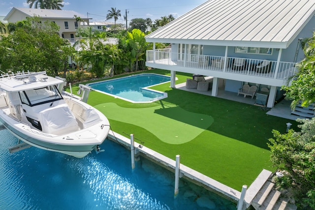 outdoor pool with boat lift, a dock, and a patio area