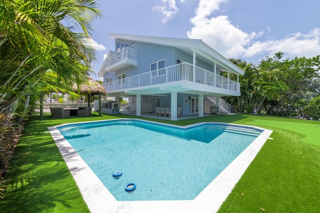 back of property with a patio, a yard, an outdoor pool, and a balcony