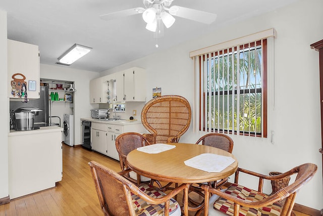 dining area with light wood-style flooring, beverage cooler, washing machine and clothes dryer, and ceiling fan
