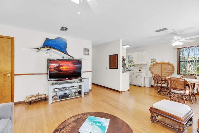living room featuring visible vents, light wood-style flooring, and a ceiling fan
