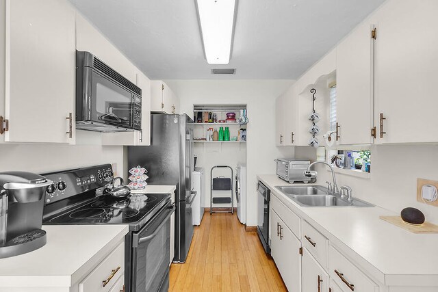 kitchen featuring light wood finished floors, visible vents, black appliances, and light countertops