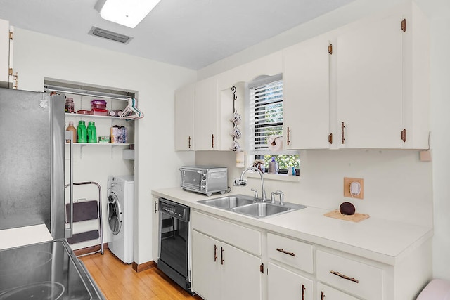 kitchen featuring a sink, washer / dryer, visible vents, freestanding refrigerator, and black dishwasher