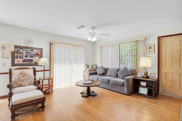 living room with light wood finished floors, visible vents, and ceiling fan