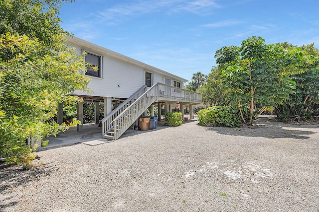 back of house featuring a wooden deck, a carport, stairs, and a patio