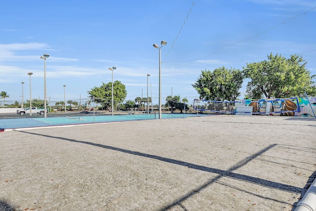 view of home's community with a tennis court, volleyball court, and fence