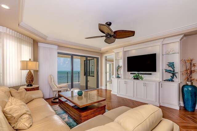 living area with ornamental molding, ceiling fan, and a raised ceiling