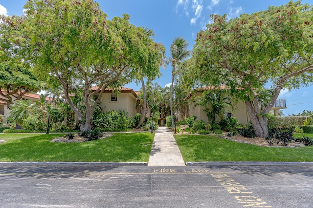 view of front of property with stucco siding, a tiled roof, and a front lawn