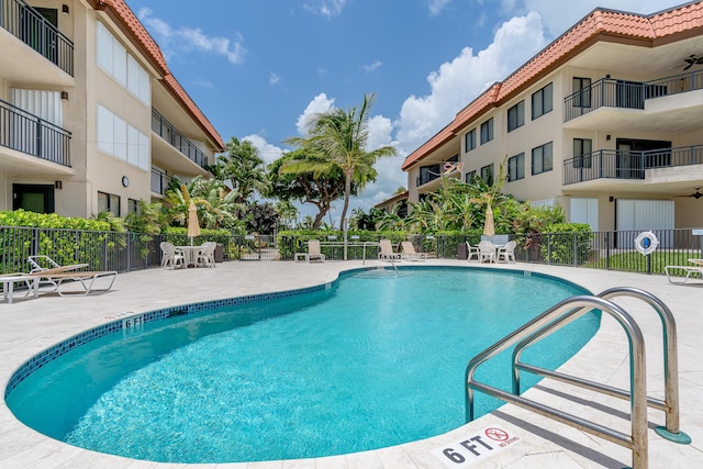 community pool with a patio and fence