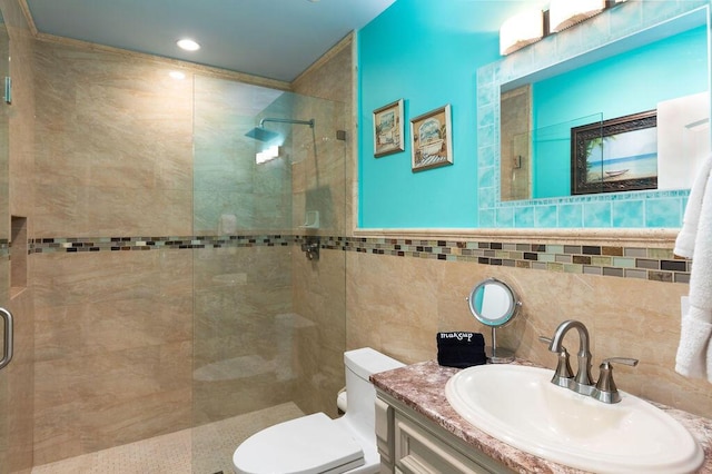 bathroom featuring vanity, a shower stall, toilet, and tile walls