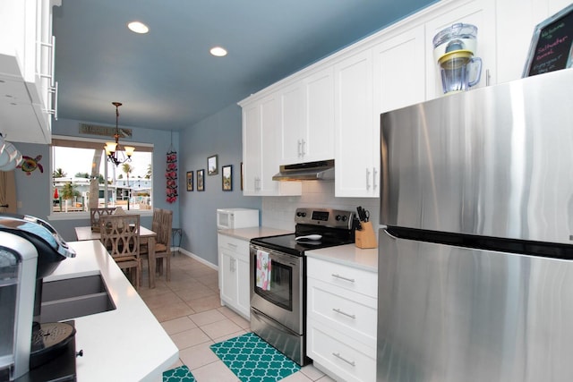 461 3rd St, Key Colony, FL 33051 - kitchen featuring appliances with stainless steel finishes, under cabinet range hood, light countertops, a chandelier, and decorative backsplash