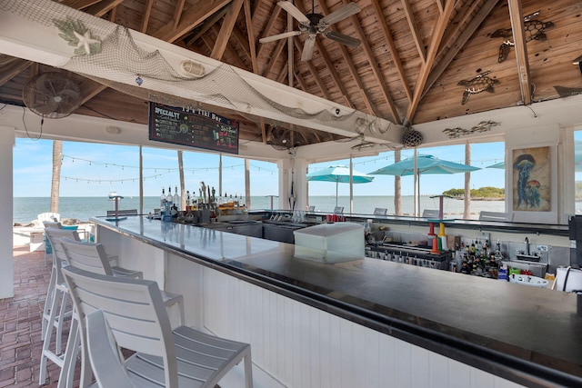 kitchen with dark countertops, wooden ceiling, a water view, vaulted ceiling with beams, and brick floor