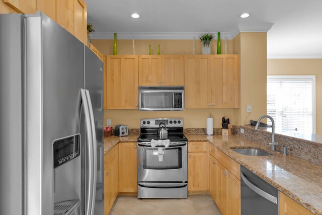 kitchen featuring crown molding, light brown cabinets, appliances with stainless steel finishes, and a sink