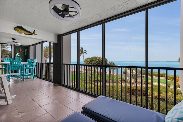 unfurnished sunroom with a water view and ceiling fan