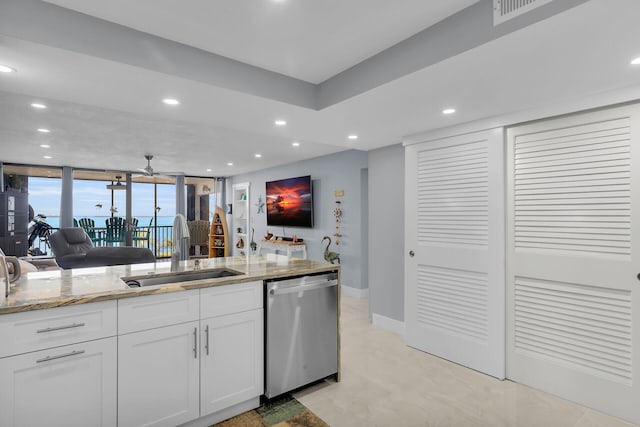 kitchen featuring white cabinets, dishwasher, light stone counters, open floor plan, and a sink