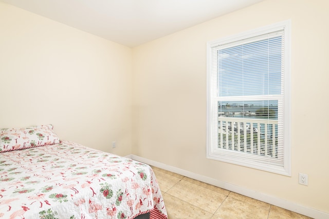 bedroom with multiple windows, baseboards, and light tile patterned floors