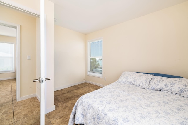 tiled bedroom with multiple windows and baseboards