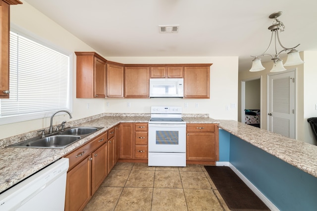 kitchen with white appliances, visible vents, a sink, light countertops, and brown cabinets