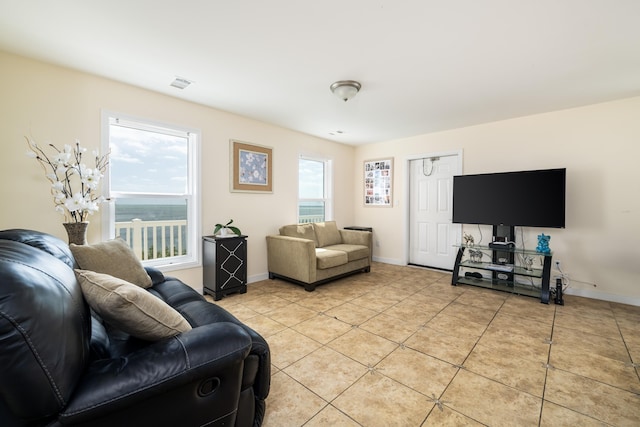 living room featuring light tile patterned floors, baseboards, visible vents, and a wealth of natural light