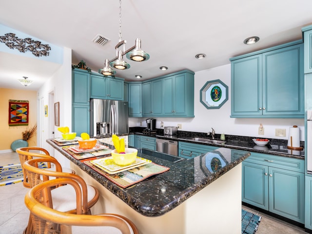 kitchen featuring visible vents, a sink, stainless steel appliances, a breakfast bar area, and light tile patterned floors