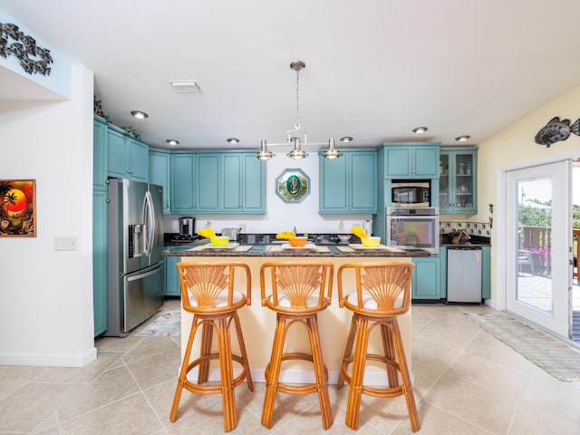 kitchen with dark countertops, visible vents, a kitchen island, and stainless steel appliances