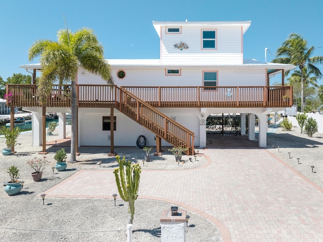 view of front of property with decorative driveway, a carport, and stairs