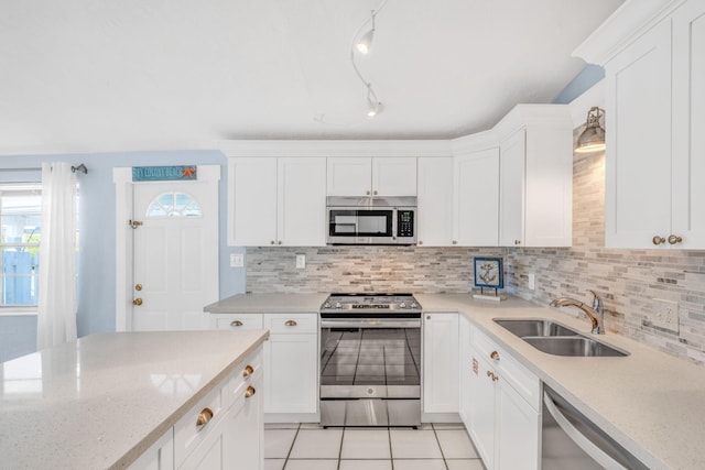 kitchen featuring decorative backsplash, white cabinetry, stainless steel appliances, and a sink