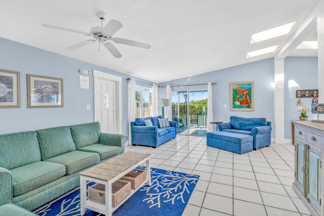 living area featuring lofted ceiling with skylight, ceiling fan, and light tile patterned flooring
