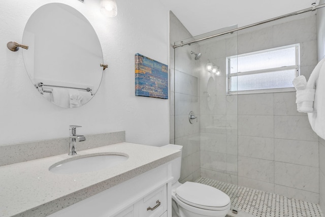 bathroom featuring toilet, tiled shower, and vanity