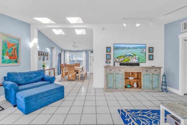 living area with light tile patterned floors, visible vents, lofted ceiling with skylight, and baseboards