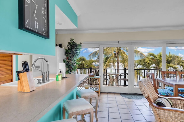 interior space with light tile patterned flooring, crown molding, and a breakfast bar