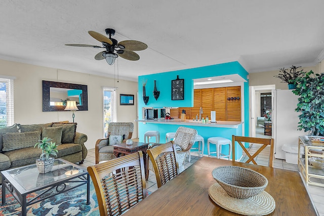 living area with a ceiling fan, ornamental molding, a healthy amount of sunlight, and wood finished floors