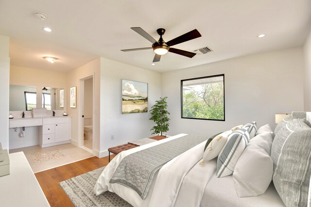 bedroom featuring visible vents, built in study area, light wood finished floors, and multiple windows