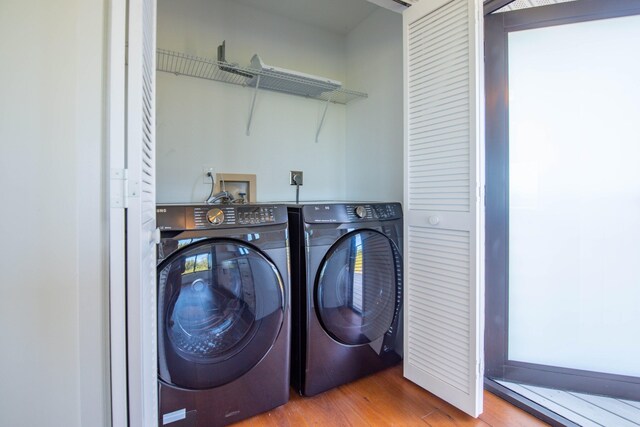 clothes washing area with laundry area, separate washer and dryer, and wood finished floors