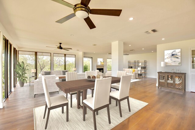 dining area with light wood finished floors, a fireplace, visible vents, and recessed lighting