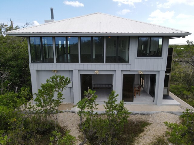 back of property featuring metal roof, a patio area, and a sunroom