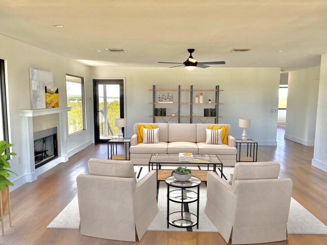 living area with visible vents, a fireplace, baseboards, and wood finished floors