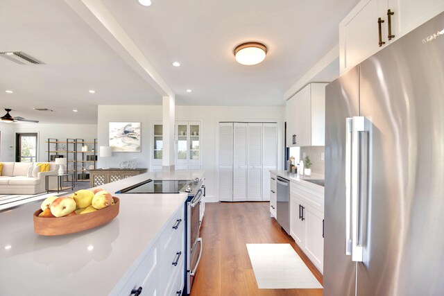 kitchen featuring stainless steel appliances, white cabinetry, visible vents, and wood finished floors