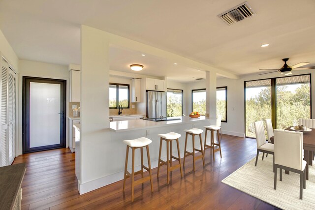 kitchen with visible vents, white cabinets, a kitchen breakfast bar, freestanding refrigerator, and light countertops