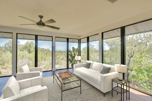 sunroom / solarium featuring a ceiling fan and a view of trees