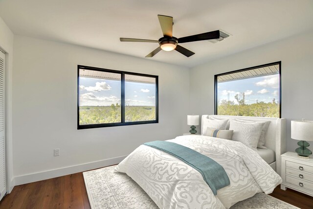 bedroom with dark wood-style floors, multiple windows, ceiling fan, and baseboards