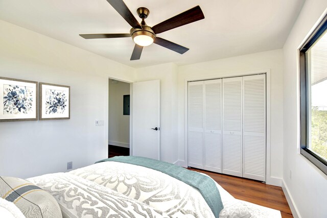 bedroom with a closet, ceiling fan, baseboards, and wood finished floors