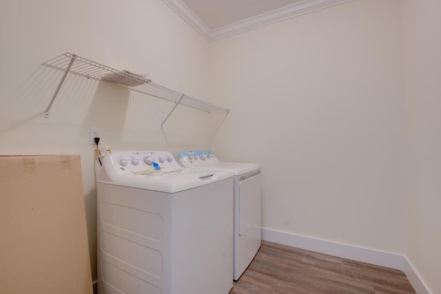 washroom with laundry area, light wood finished floors, baseboards, washer and clothes dryer, and ornamental molding