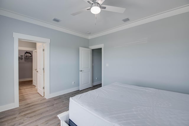 bedroom with ornamental molding, light wood-type flooring, visible vents, and baseboards