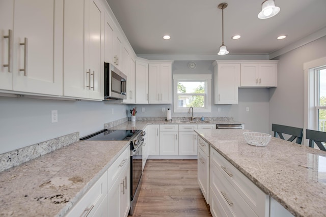 kitchen with light stone counters, a sink, white cabinetry, appliances with stainless steel finishes, and decorative light fixtures